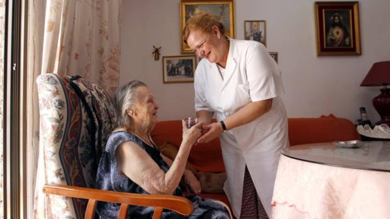 Una trabajadora de ayuda a domicilio atiende a una anciana en Córdoba