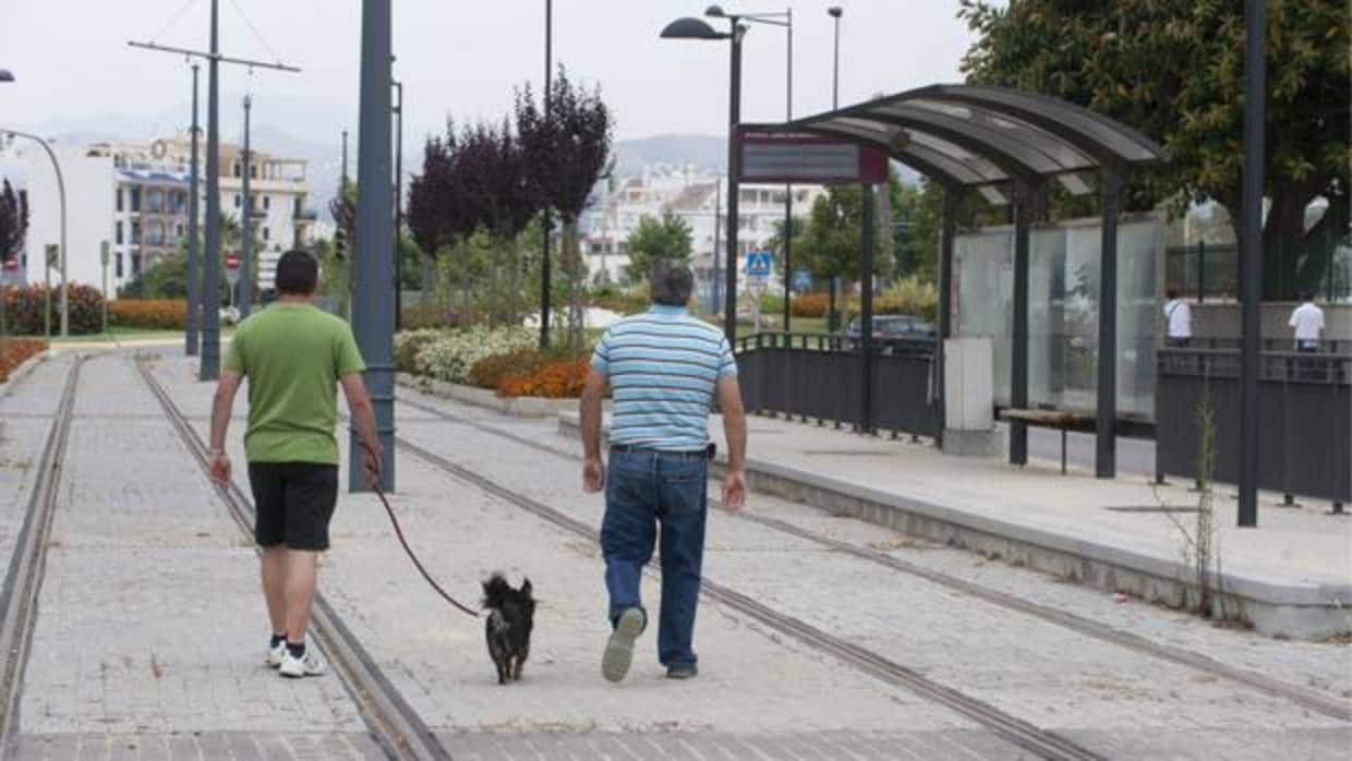 Dos personas transitan por las vías del abandonado tranvía de Vélez-Málaga