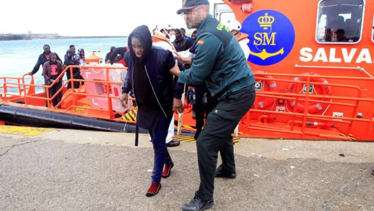 Un guardia civil ayuda a bajar a una mujer llegada el martes a Tarifa, Cádiz