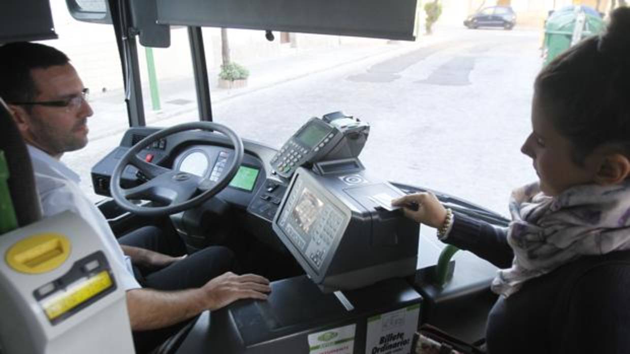 Un conductor de autobús espera a que una usuaria valide su título