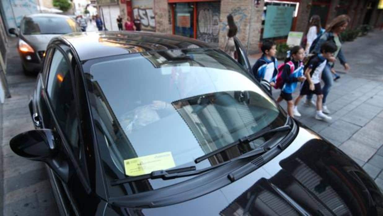 Un coche exhibe su permiso para acceder al Centro transportando a escolares