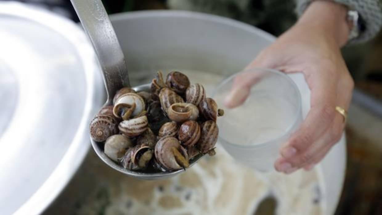 Una persona sirve un vaso de caracoles en un puesto de Córdoba