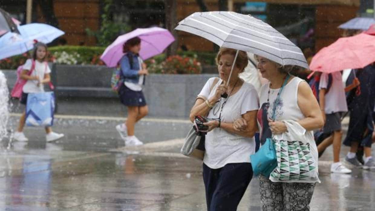 Lluvia y niños, al fondo, con sus paraguas a la salida del colegio