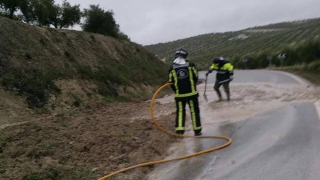 Bomberos durante las labores de limpieza de la carretera A-3125 en Baena