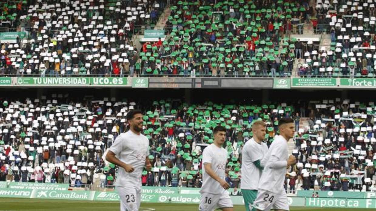 Los aficionados del Córdoba CF muestran cartulinas blancas y verdes en El Arcángel