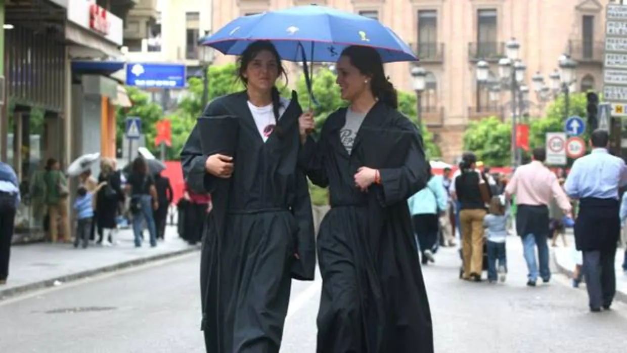 Dos nazarenas de los Dolores con un paraguas en una edición anterior del Viernes Santo cordobés