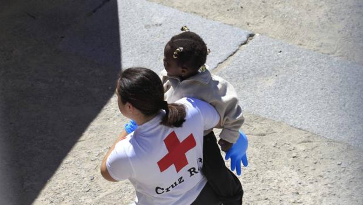 Imagen de archivo de una voluntaria de Cruz Roja asistiendo a una pequeña que llegó en patera a Tarifa