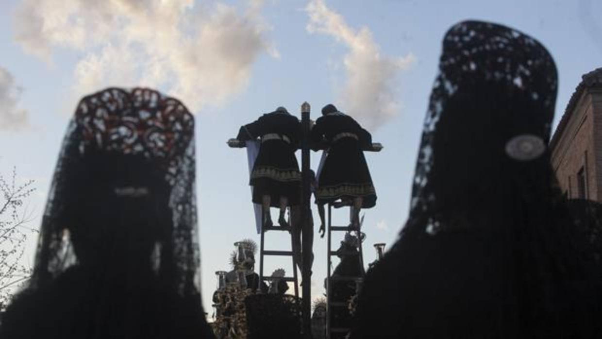 Dos mujeres que acompañan con mantilla en la procesión del Descendimiento miran al Cristo