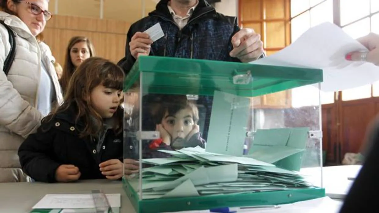 Unos niños miran dentro de una urna al Parlamento de Andalucía en las anteriores elecciones del 22 de marzo de 2015