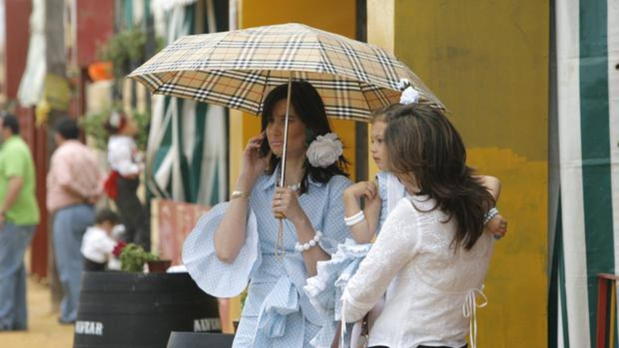 Una gitana bajo un paraguas en la puerta de una caseta de la Feria de Córdoba