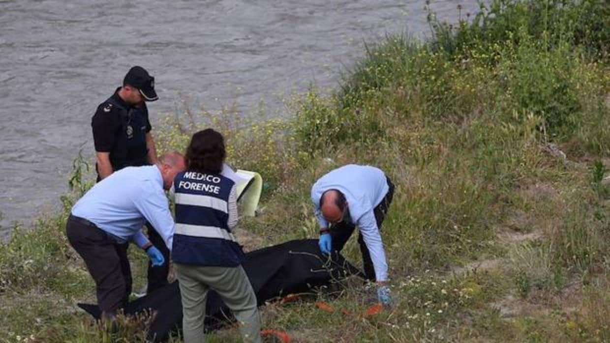 Equipo forense realizando el levantamiento del cadáver en la ribera del río Genil