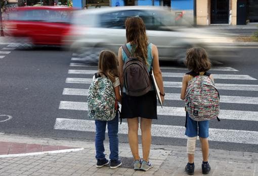 Una mujer acompaña a dos niñas al colegio
