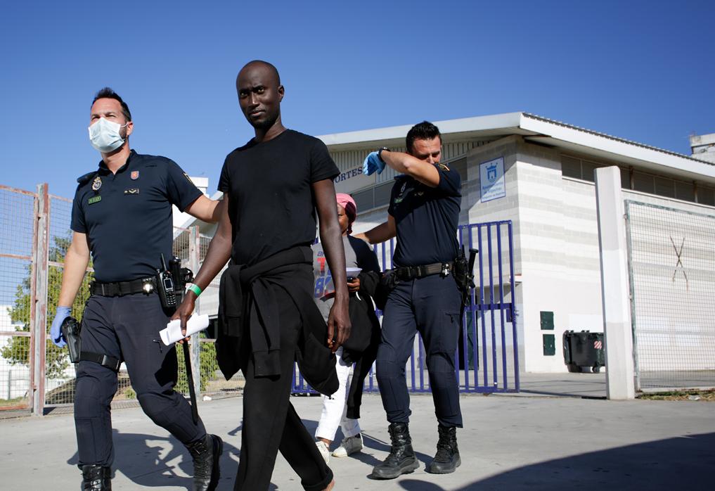 Policías trasladan a inmigrantes en el pabellón polideportivo de Algeciras.