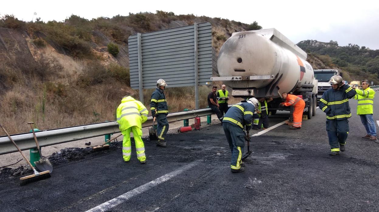 Bomberos limpian la zona junto al camión cisterna incendidado.