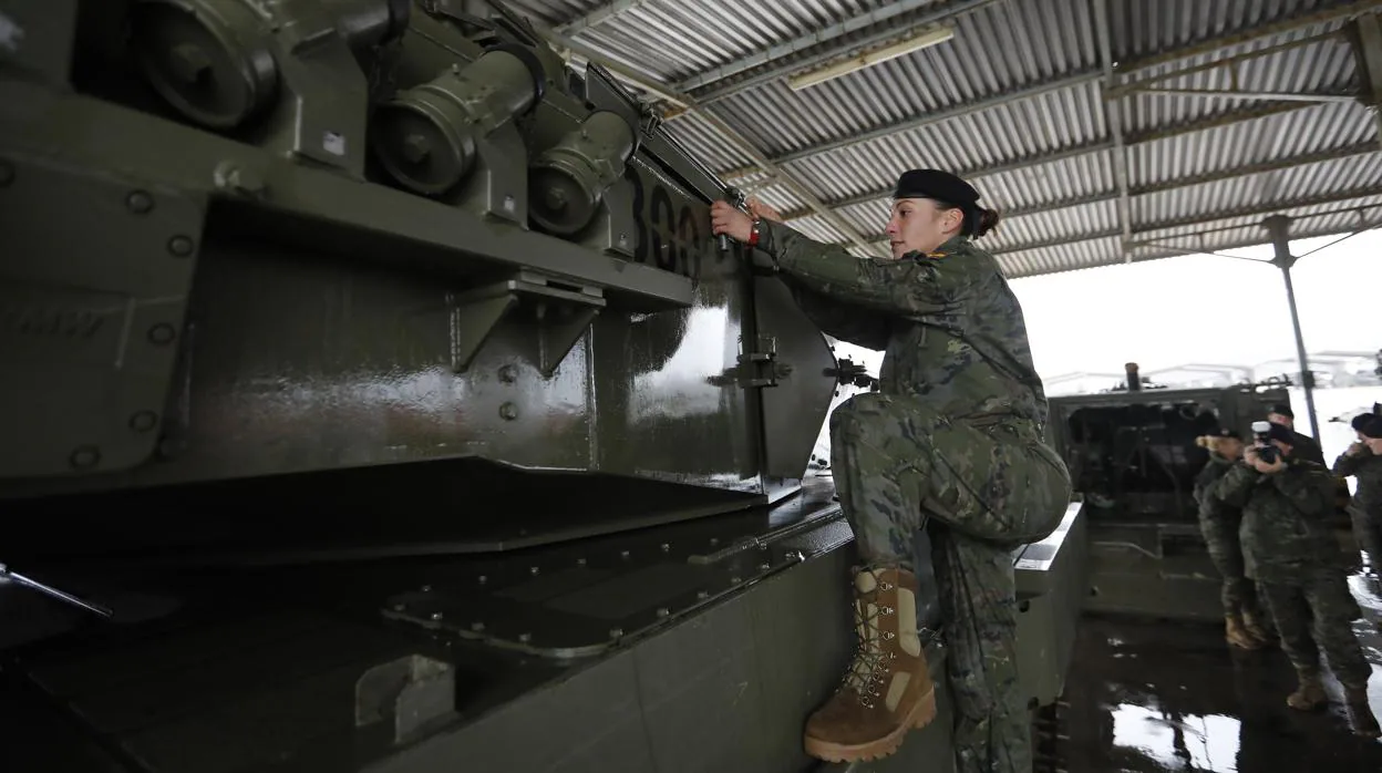 Una militar sube a un carro de combate en la base militar de Cerro Muriano