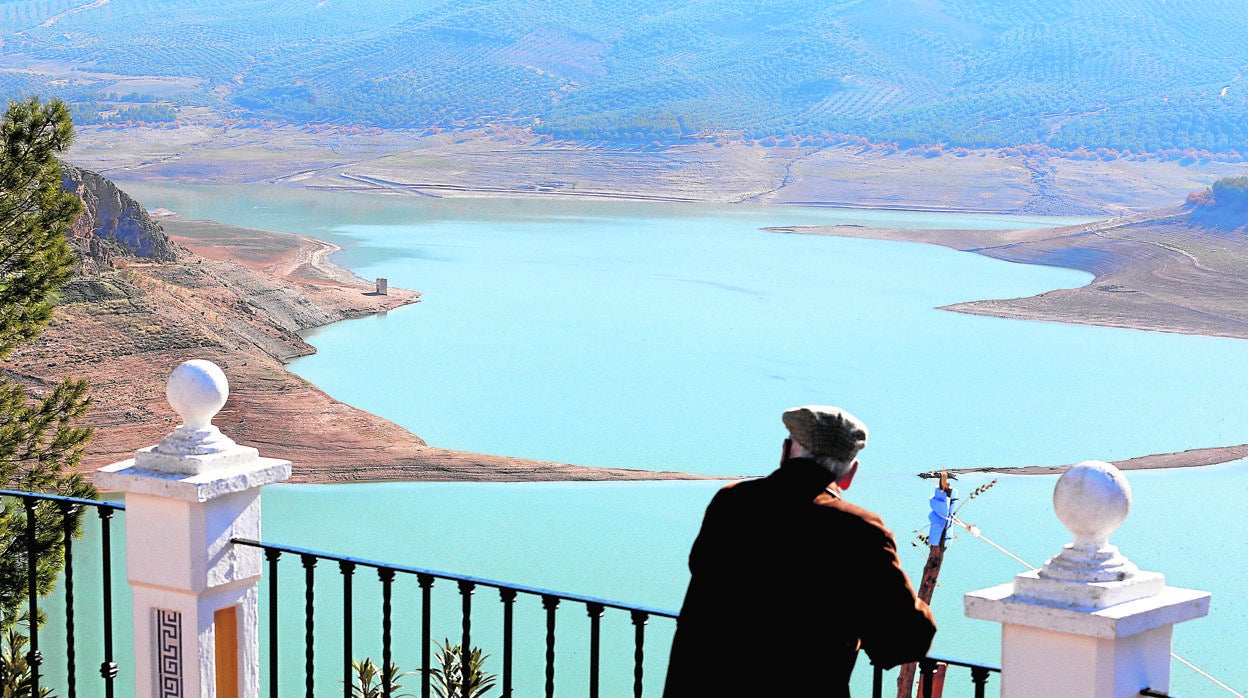 Un hombre se asoma al pantano de Iznájar desde el mirador del pueblo