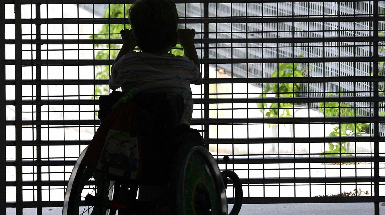 Un niño en silla de ruedas mira a un patio