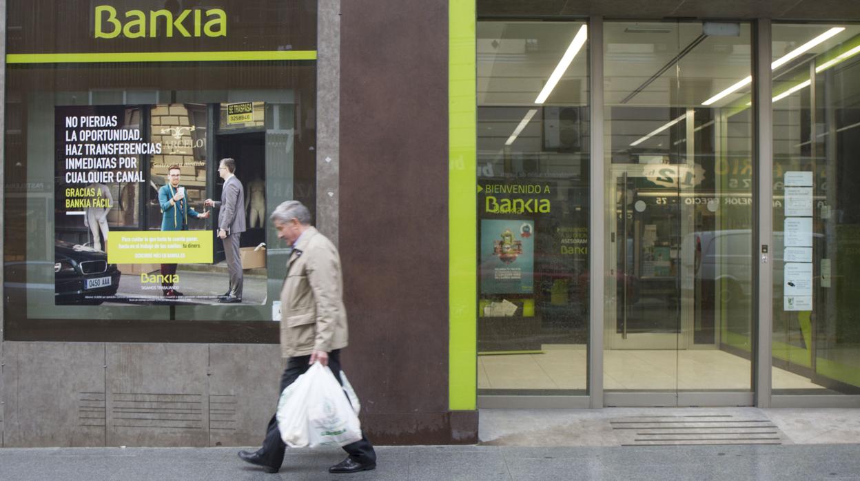 Un hombre pasa delante de una oficina de Bankia