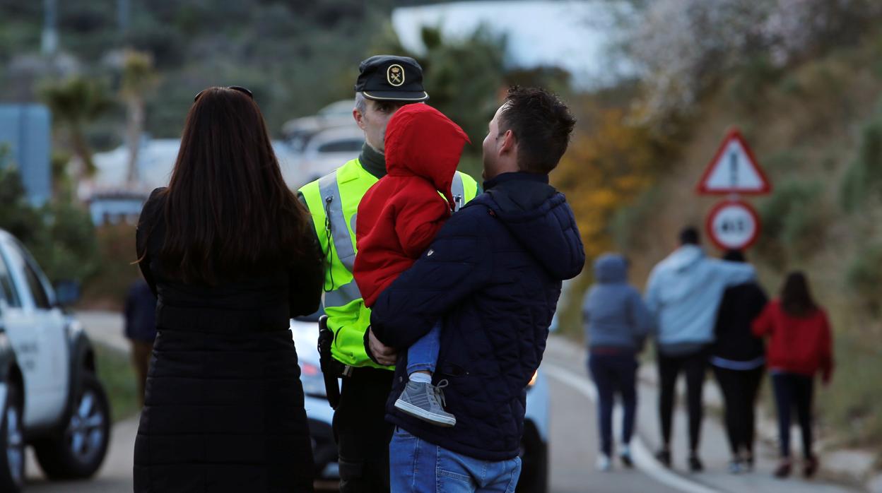 Un agente de la Guardia Civil charla con una familia cerca del lugar del suceso