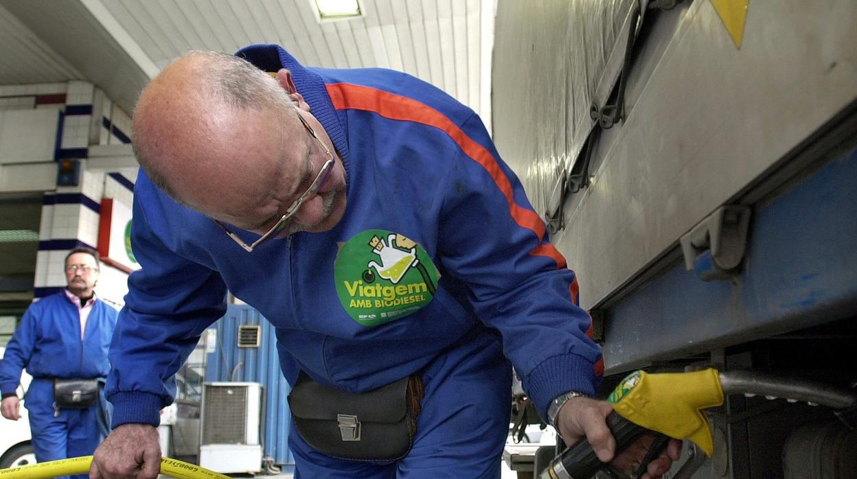 Un empleado llena el depósito de un camión de transporte de mercancias agrícolas