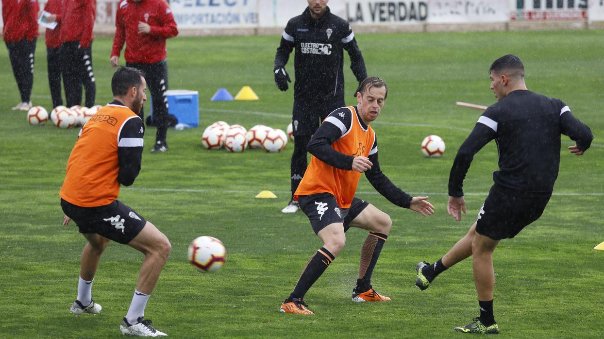 Varios jugadores del Córdoba CF pelotean durante el entrenamiento bajo la lluvia