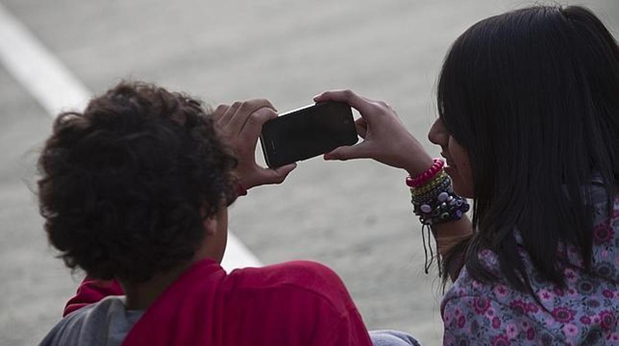 Dos jóvenes juegan con un teléfono móvil