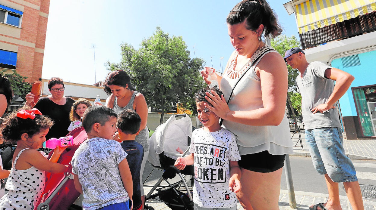 Una mujer refresca a un niño a las puertas de un colegio