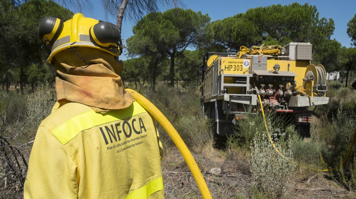 Un bombero forestal tira una manguera de uno de los camiones que prestan servicio en el Infoca