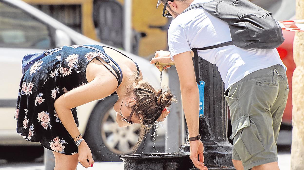 Una joven se refresca en una fuente pública