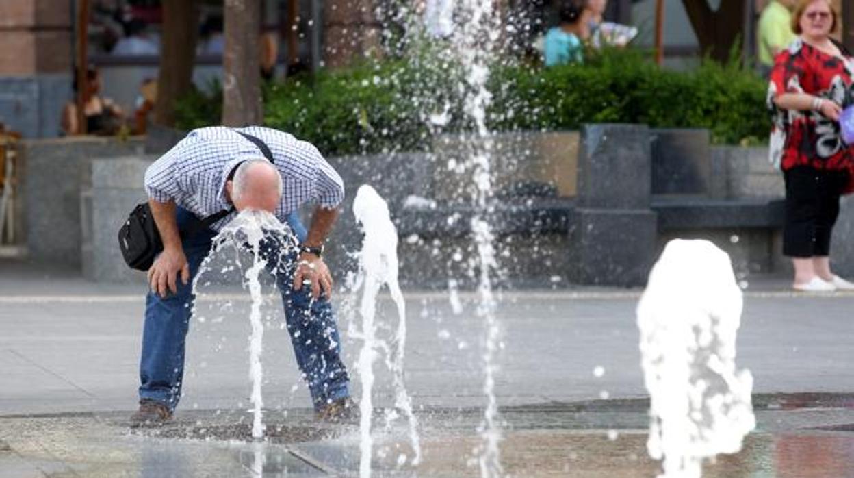 Un hombre se refresca en una fuente de Córdoba