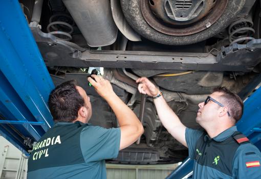 Dos agentes de la Guardia Civil inspeccionan los bajos de un vehículo