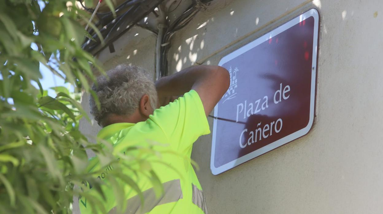 Operarios colocando de nuevo la placa a la plaza de Cañero