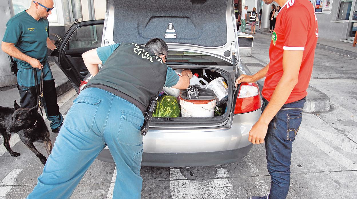 Dos agentes revisan el maletero de un coche en un puesto fronterizo