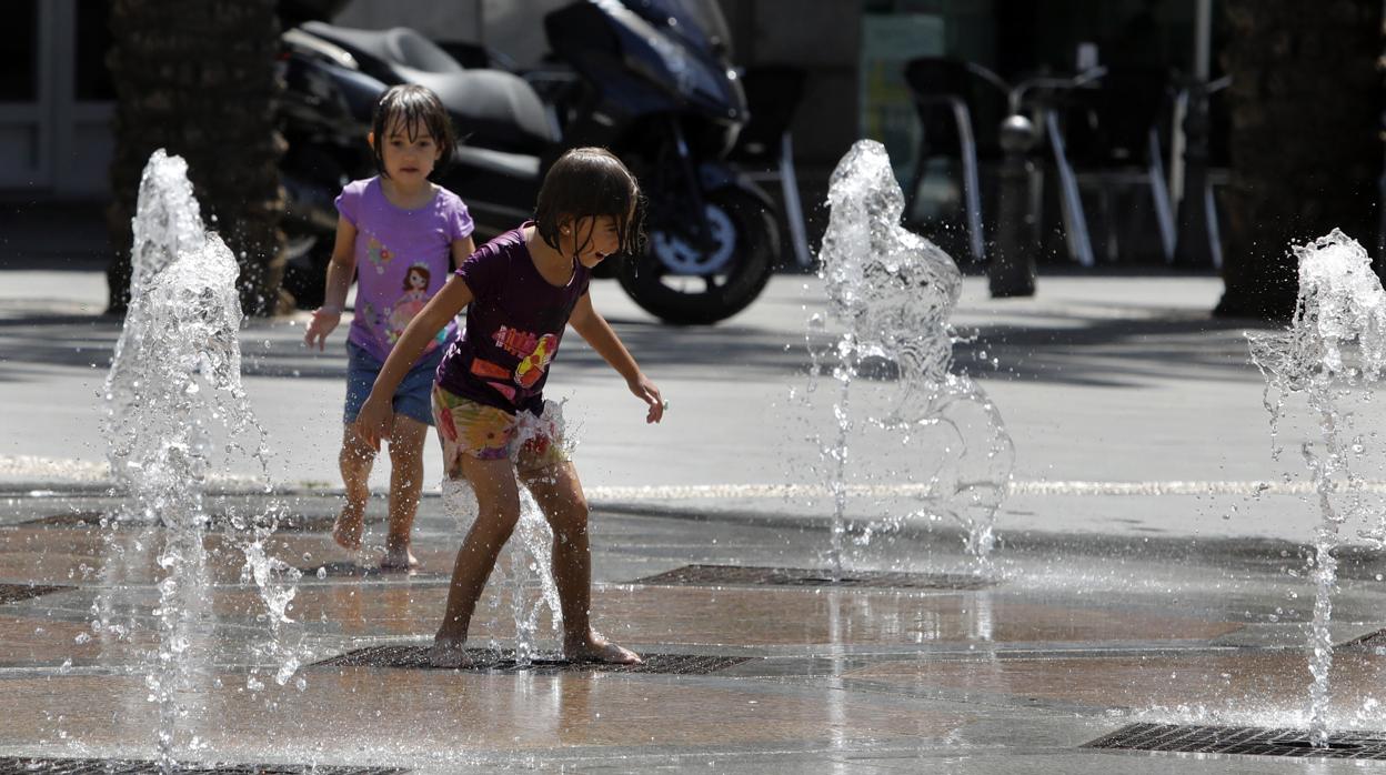 Dos niñas se refrescan en una fuente