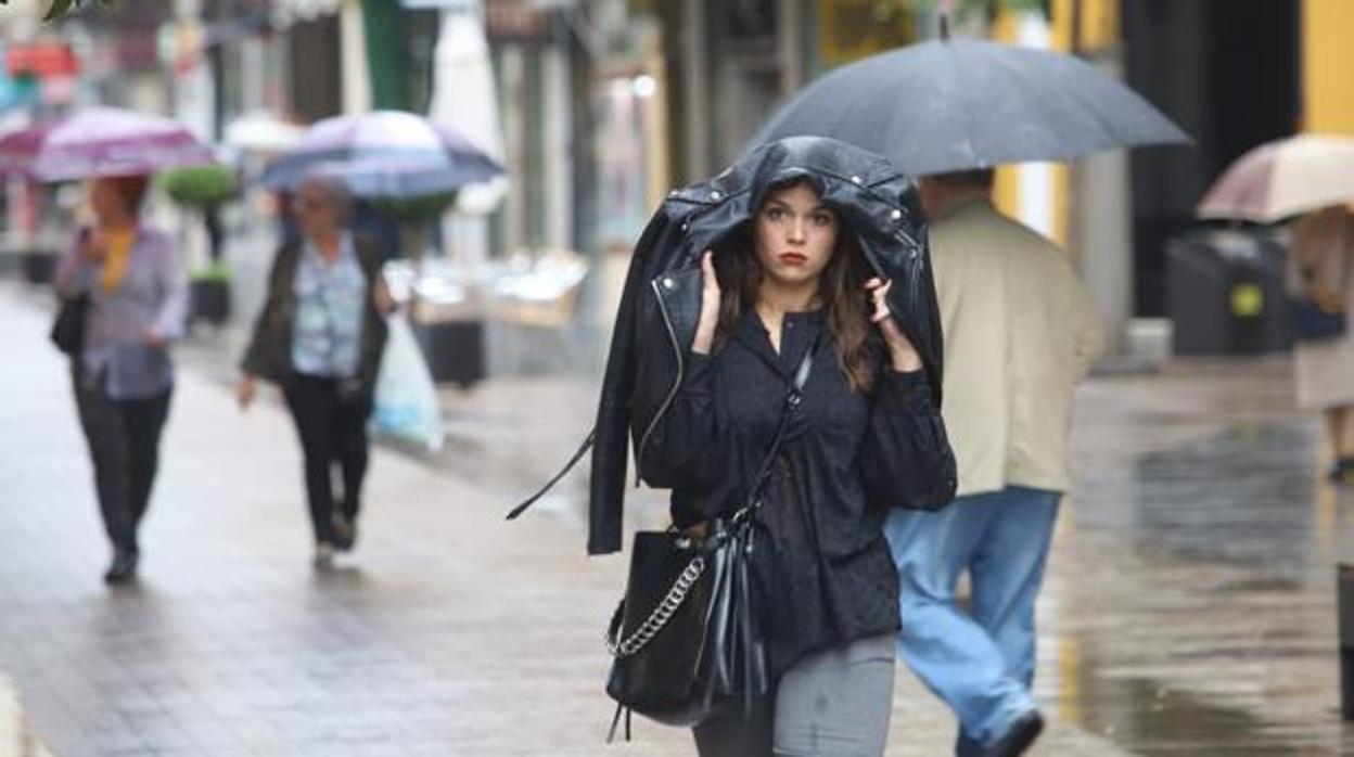 Una chica se resguarda de la luvia en una foto de archivo