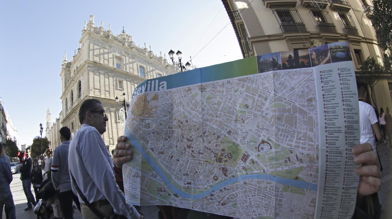 Turistas despliegan un mapa de Sevilla en el centro de la capital andaluza