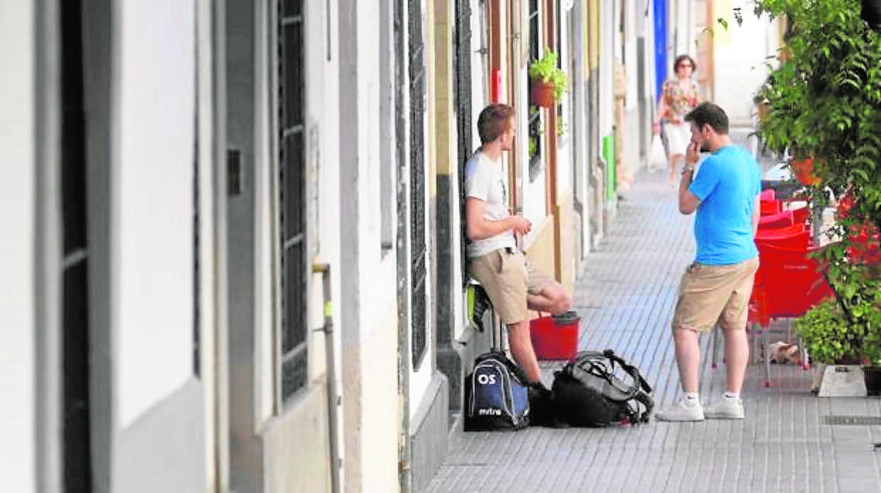 Dos jóvenes turistas esperan a la puerta de una vivienda turística