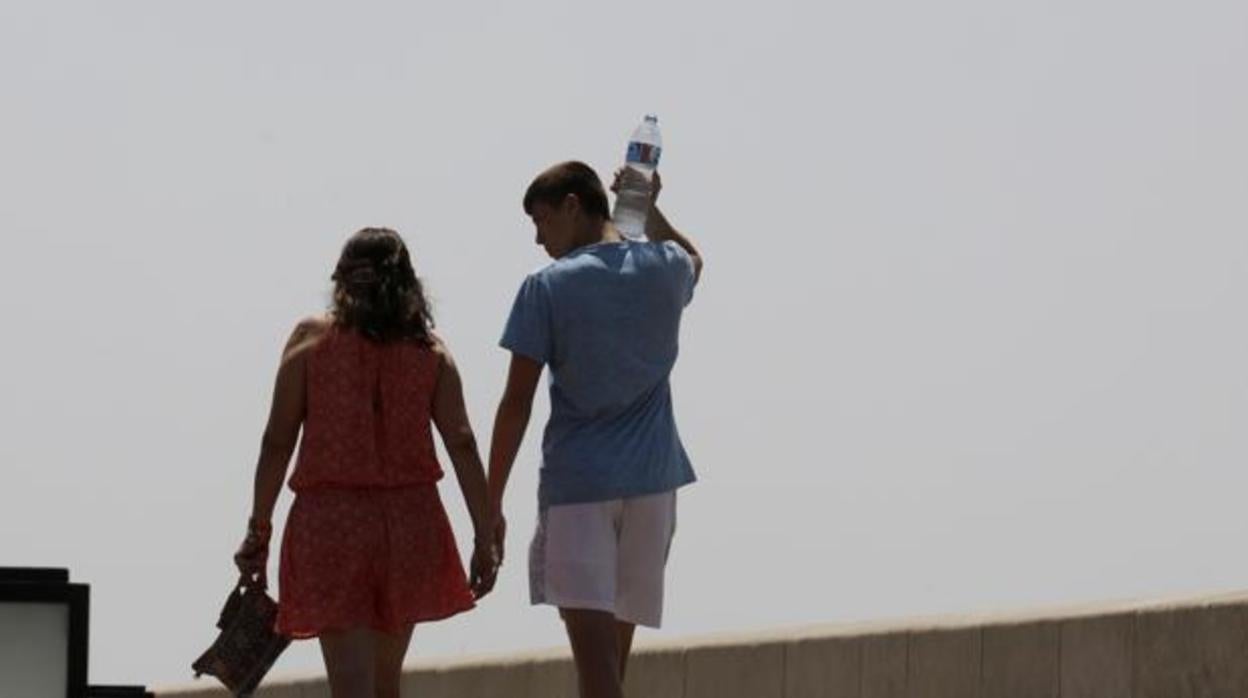 Una pareja paseando por el Puente Romano en una jornada de calor