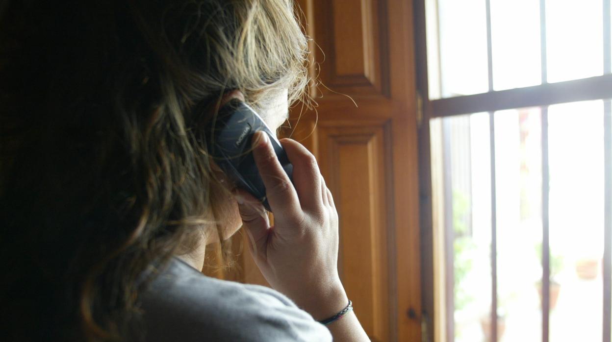 Una mujer habla por teléfono desde el interior de su vivienda