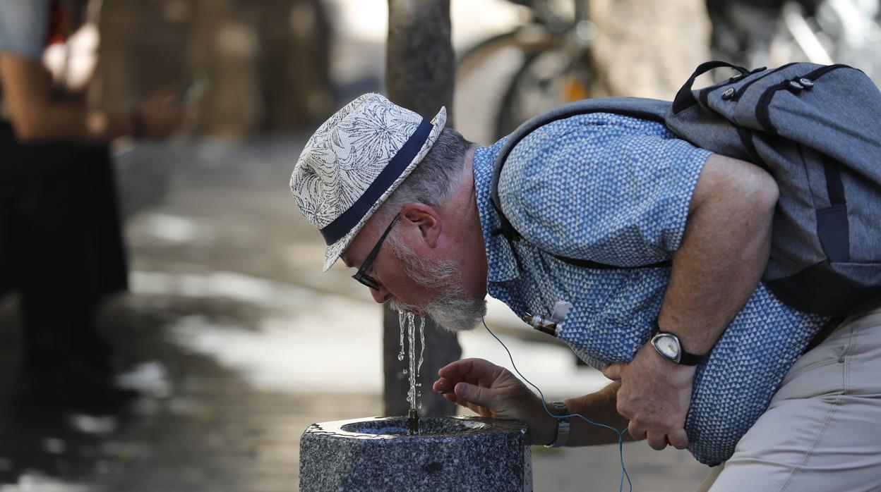 Un turista se refresca bebiendo agua de una fuente