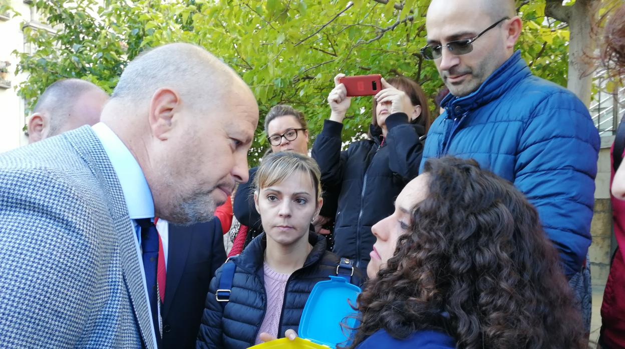 Una madre muestra una tartera vacía al consejero para reprocharle el cierre de los comedores escolares