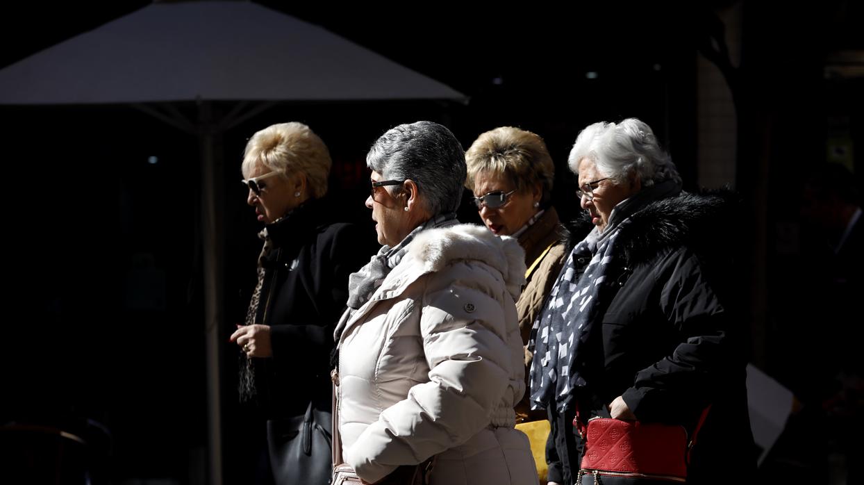 Cuatro mujeres caminan, bien abrigadas, bajo el sol de invierno