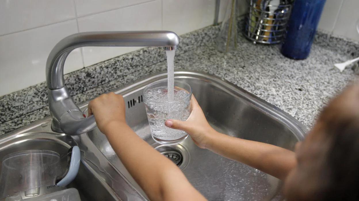 Una niña toma agua de un grifo