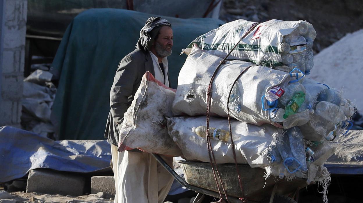 Un yemení empuja una carretilla repleta de plásticos para reciclar en Sanaa