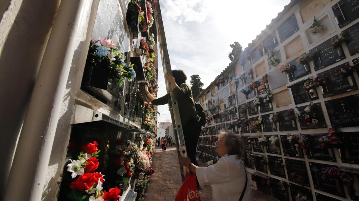 Dos mujeres adecentan una lápida en el cementerio de San Rafael