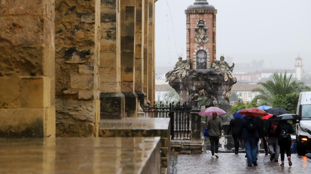 Varias personas pasean bajo la lluvia por el entorno de la Mezquita-Catedral