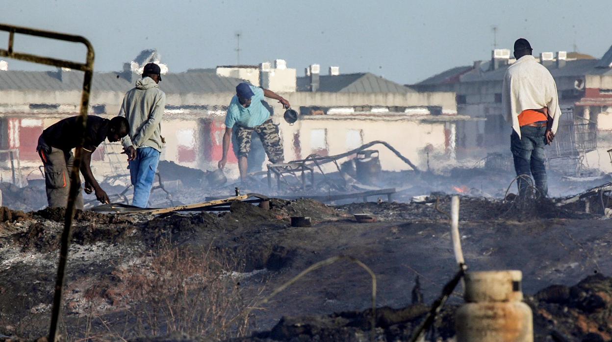 Temporeros buscan sus enseres tras un incendio en el asentamiento que vivían