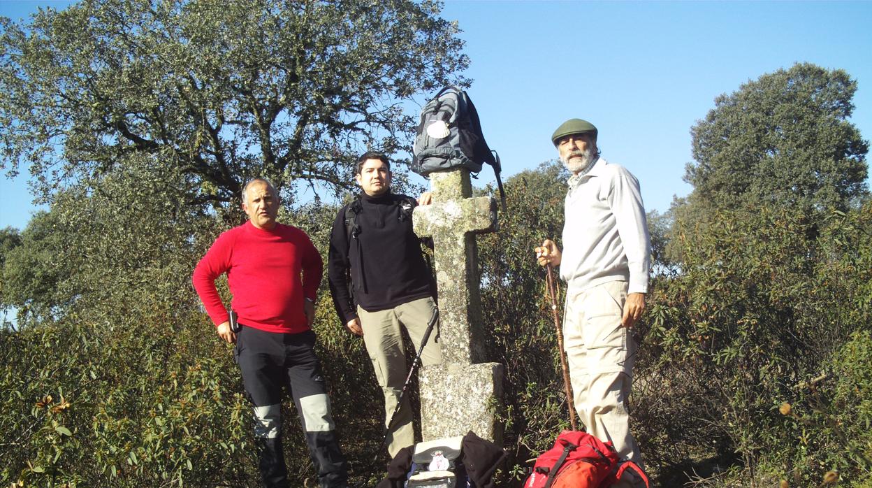 Tres peregrinos posan ante una cruz en el Puerto del Calatraveño