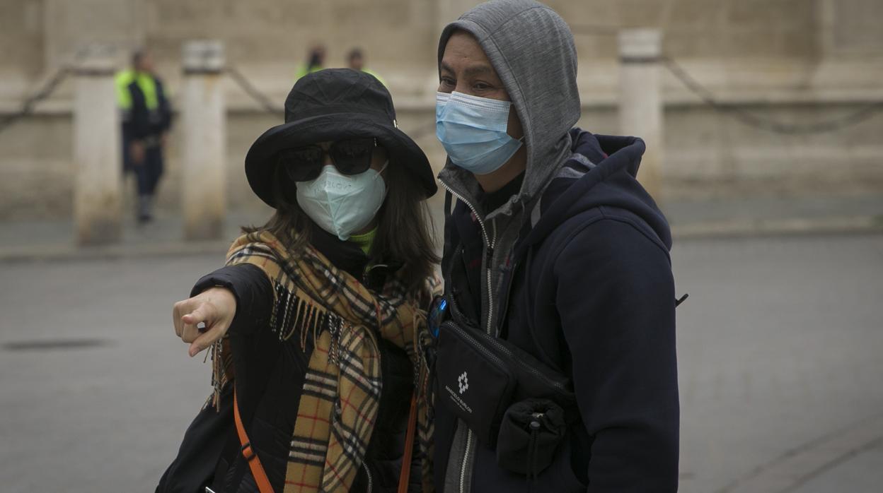 Dos turistas protegidos por unas mascarillas en la capital hispalense