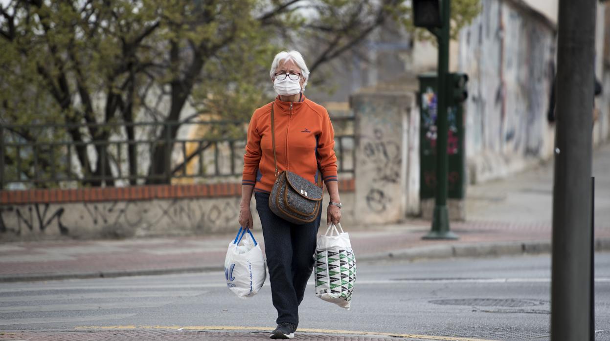 Una mujer, con mascarilla, por las calles de Granada